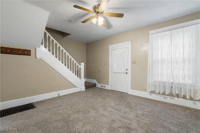 foyer entrance featuring ceiling fan and carpet floors