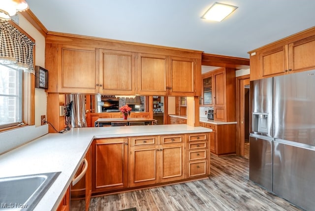 kitchen with light hardwood / wood-style flooring, ornamental molding, kitchen peninsula, and appliances with stainless steel finishes