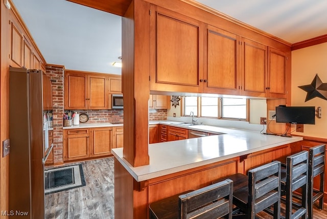 kitchen featuring kitchen peninsula, refrigerator, decorative backsplash, hardwood / wood-style flooring, and sink