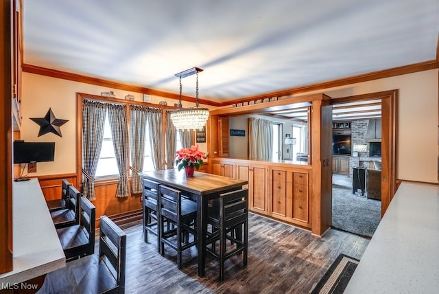 dining area featuring ornamental molding, an inviting chandelier, wooden walls, and dark hardwood / wood-style floors