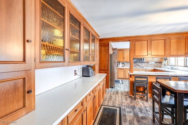 kitchen with sink, dark hardwood / wood-style flooring, decorative backsplash, and stainless steel refrigerator