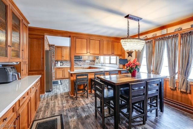 kitchen with stainless steel appliances, a notable chandelier, pendant lighting, dark wood-type flooring, and tasteful backsplash