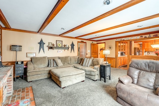 living room with ornamental molding, wood walls, carpet floors, and beam ceiling