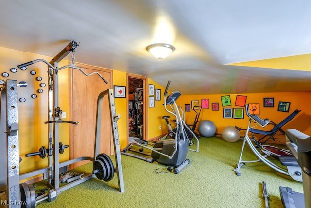 workout room with vaulted ceiling and carpet flooring