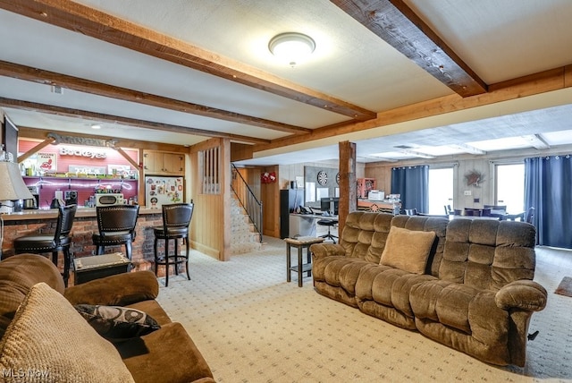 carpeted living room with indoor bar, beam ceiling, and wooden walls