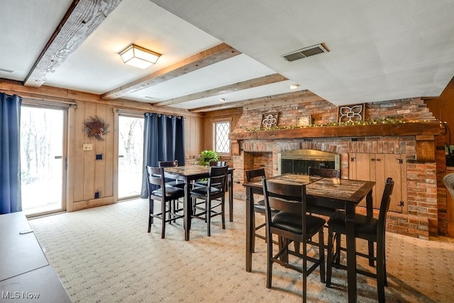 dining space with beam ceiling, wood walls, and a fireplace