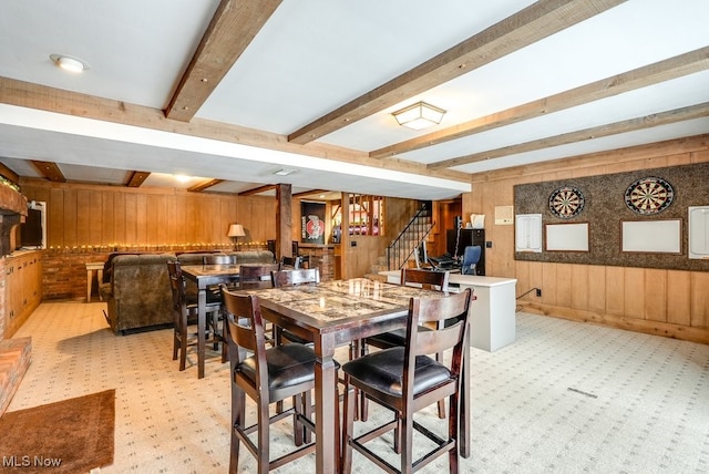 carpeted dining space with wooden walls and beamed ceiling