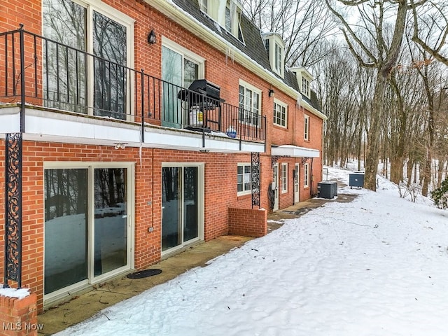 snow covered rear of property with central AC unit