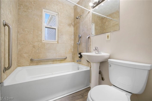 bathroom featuring tiled shower / bath combo and toilet