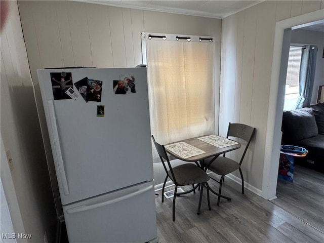 dining area with light hardwood / wood-style floors and wooden walls