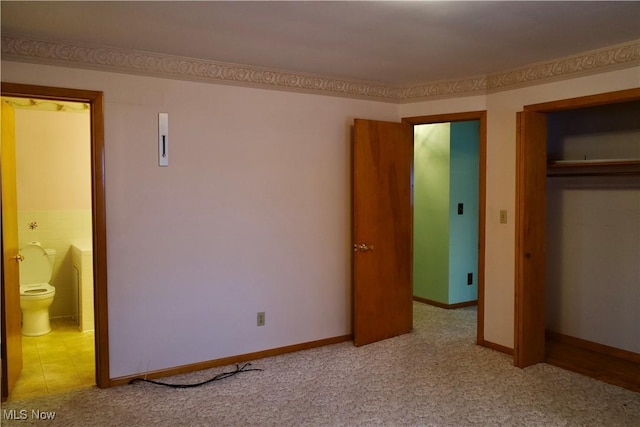 unfurnished bedroom featuring ensuite bathroom, a closet, and light colored carpet