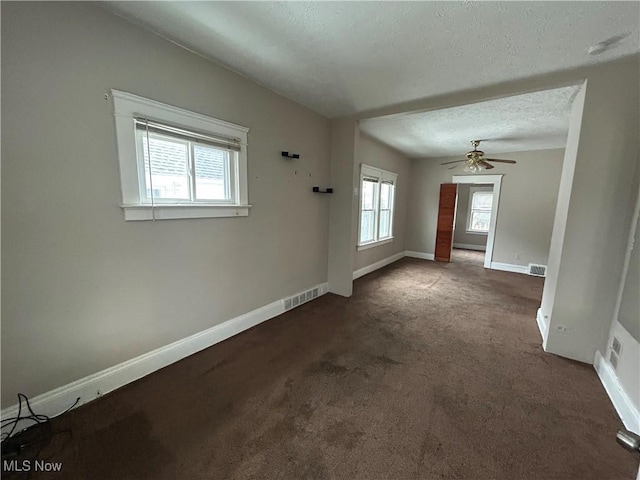 unfurnished room featuring a textured ceiling, ceiling fan, and dark carpet