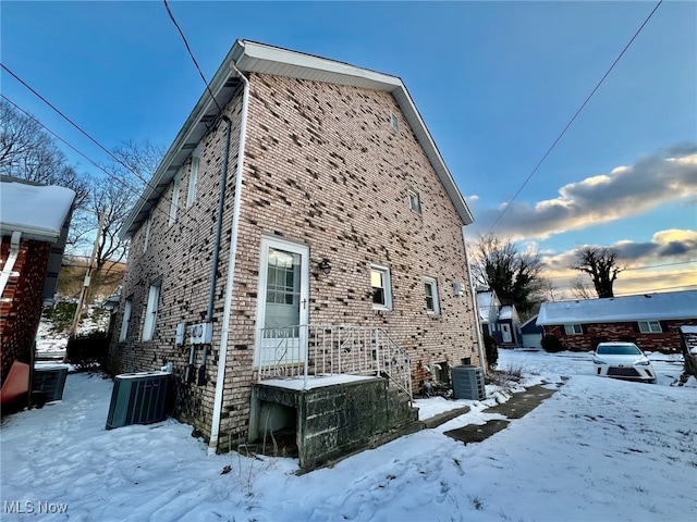 snow covered property featuring central AC