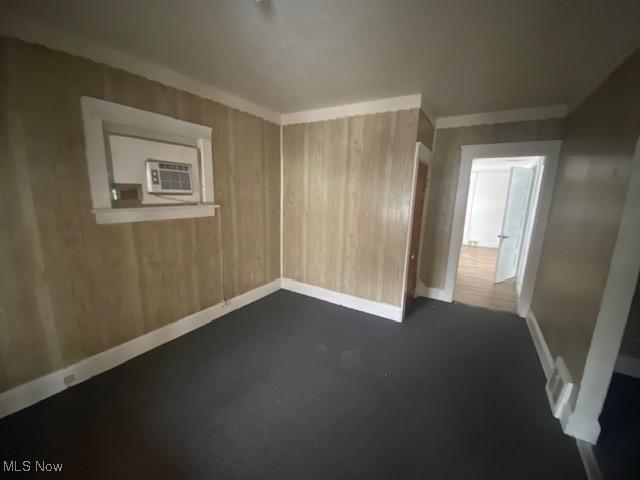 unfurnished room featuring ornamental molding and wooden walls