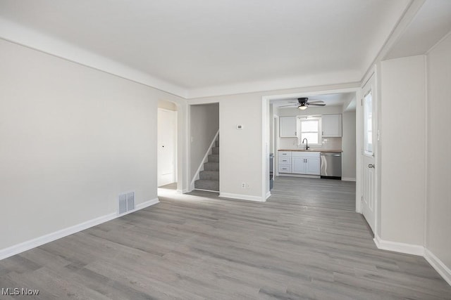 unfurnished living room featuring ceiling fan, sink, and light hardwood / wood-style flooring