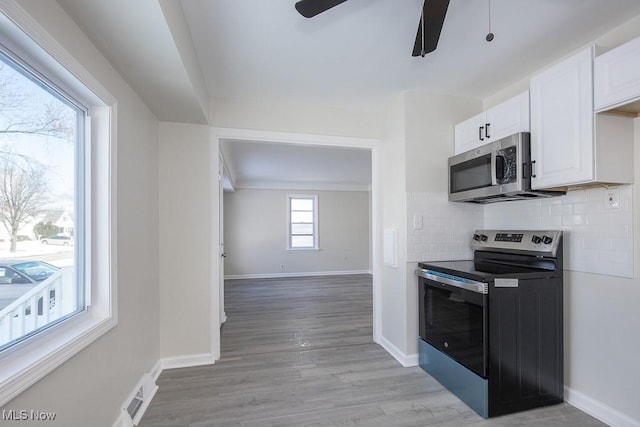 kitchen featuring white cabinetry, stainless steel appliances, light hardwood / wood-style floors, backsplash, and ceiling fan