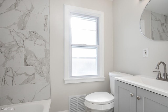 full bathroom featuring a wealth of natural light, tiled shower / bath combo, vanity, and toilet