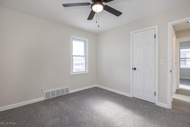 carpeted empty room with ceiling fan and plenty of natural light