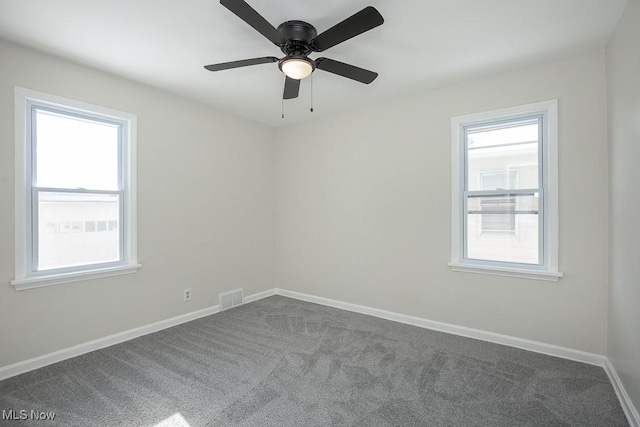 empty room with carpet floors, ceiling fan, and a wealth of natural light