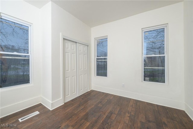 unfurnished bedroom featuring dark hardwood / wood-style flooring and a closet