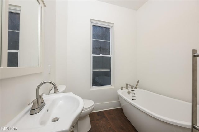 bathroom featuring wood-type flooring, toilet, sink, and a bathtub