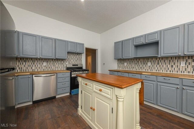 kitchen featuring butcher block counters, dark wood-type flooring, tasteful backsplash, and appliances with stainless steel finishes