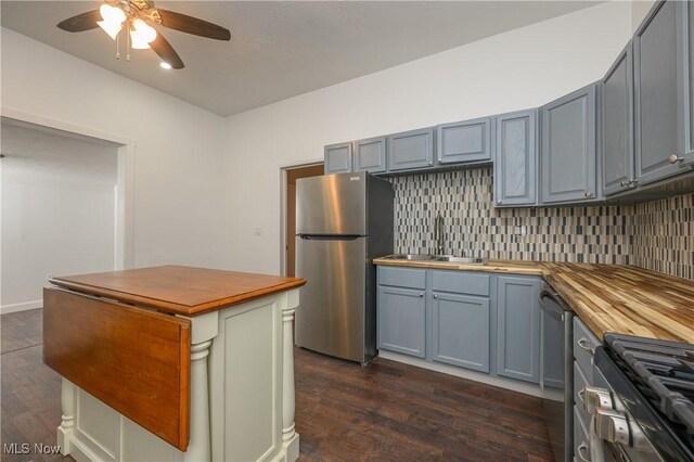 kitchen featuring dark wood-type flooring, sink, butcher block countertops, appliances with stainless steel finishes, and backsplash