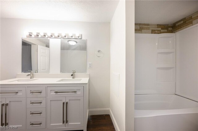 bathroom with vanity, wood-type flooring, a textured ceiling, and  shower combination