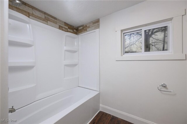 bathroom with hardwood / wood-style flooring and shower / washtub combination