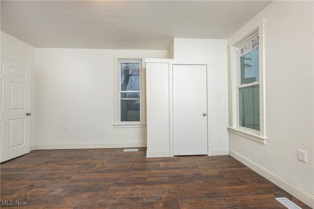 unfurnished bedroom featuring dark wood-type flooring and a textured ceiling