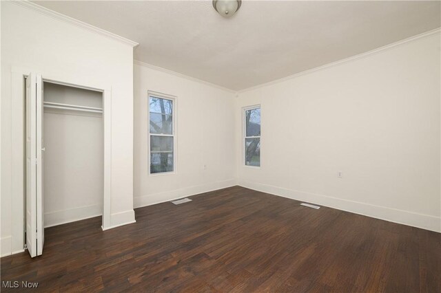 unfurnished bedroom featuring ornamental molding, dark wood-type flooring, and a closet