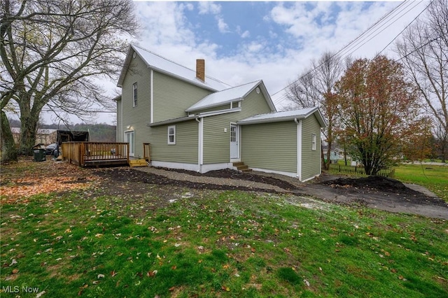 rear view of property featuring a yard and a deck