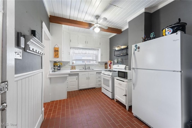 kitchen with white appliances, vaulted ceiling with beams, ceiling fan, sink, and white cabinetry