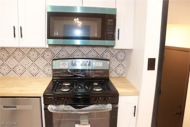 kitchen featuring butcher block countertops, backsplash, white cabinets, and black gas range oven