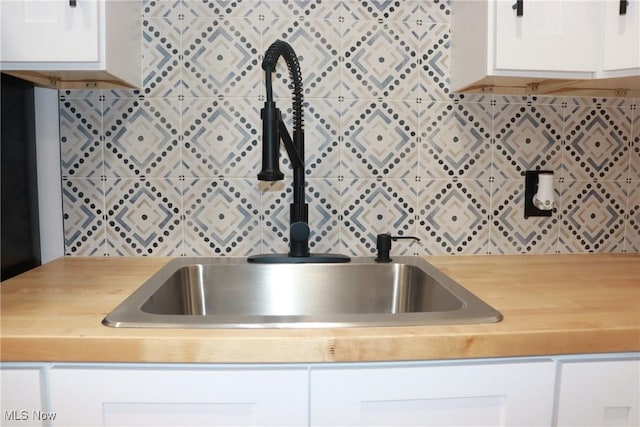 kitchen with white cabinetry, decorative backsplash, and sink