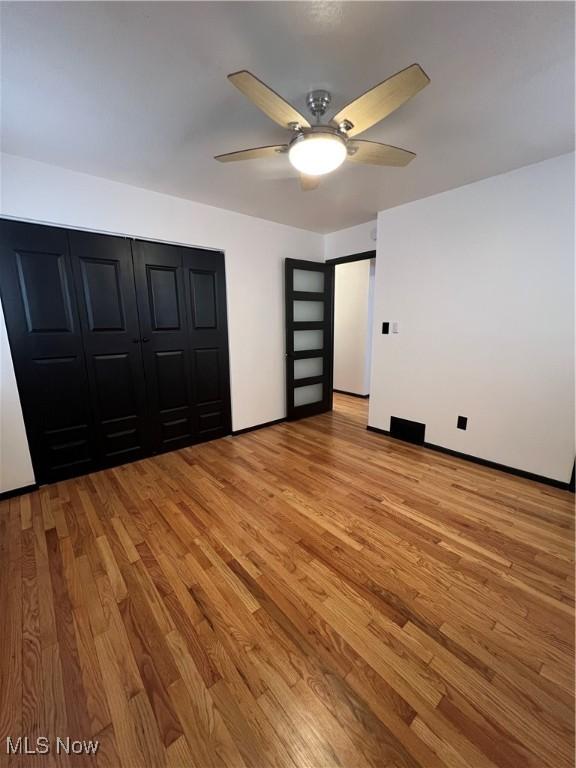 unfurnished bedroom with ceiling fan, a closet, and light hardwood / wood-style flooring