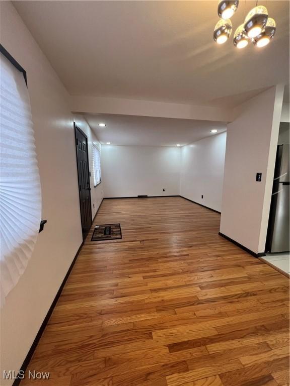 unfurnished room featuring a chandelier and light hardwood / wood-style flooring