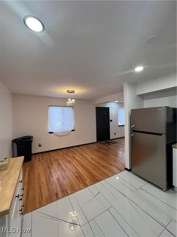 kitchen with light wood-type flooring, an inviting chandelier, wooden counters, and stainless steel refrigerator