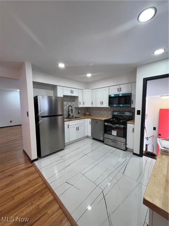 kitchen featuring stainless steel appliances, white cabinetry, tasteful backsplash, and sink