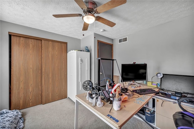 office area with a textured ceiling, light carpet, and ceiling fan