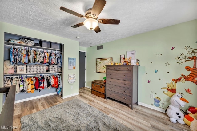 bedroom with a textured ceiling, ceiling fan, a closet, and hardwood / wood-style floors