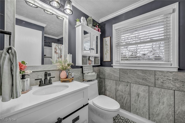 bathroom featuring toilet, a textured ceiling, tile walls, crown molding, and vanity