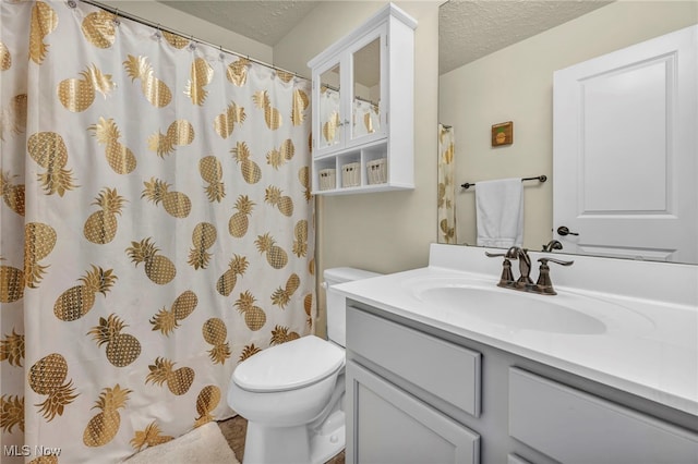 bathroom featuring vanity, a textured ceiling, and toilet