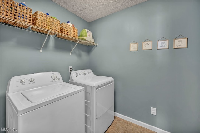 clothes washing area with separate washer and dryer, a textured ceiling, and light tile patterned floors