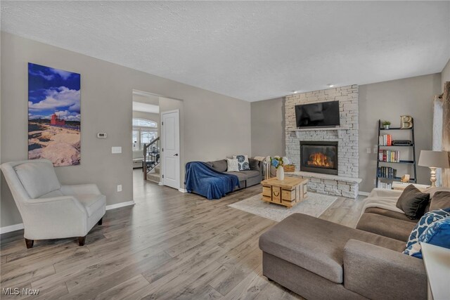 living room featuring a textured ceiling, light hardwood / wood-style flooring, and a fireplace