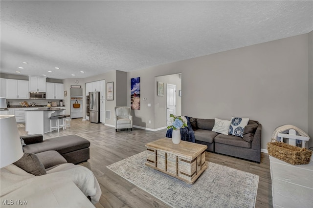 living room with a textured ceiling and light hardwood / wood-style flooring