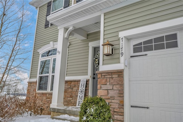 snow covered property entrance featuring a garage