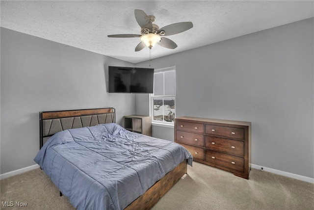 bedroom featuring ceiling fan, light colored carpet, and a textured ceiling