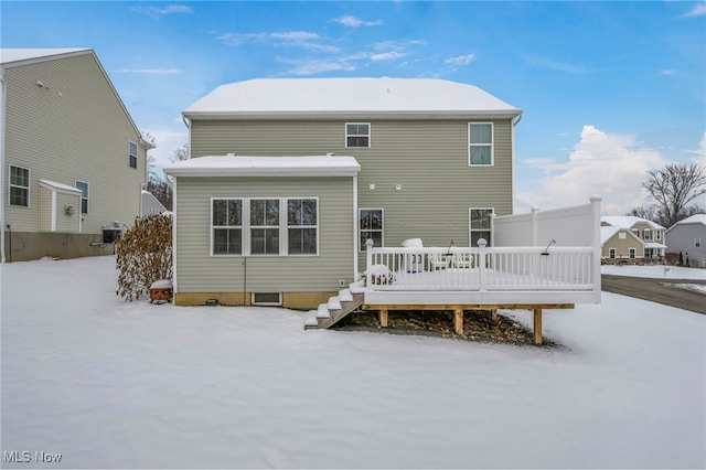 snow covered back of property with a wooden deck