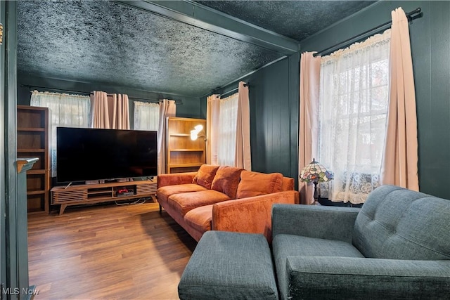 living room featuring a textured ceiling, hardwood / wood-style flooring, and beam ceiling